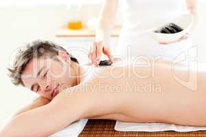 Smiling young man receiving hot stone on his back