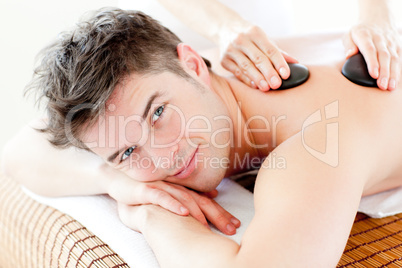 Handsome man receiving a back massage with hot stone