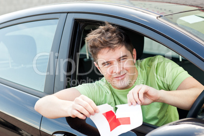 Happy young man cutting a "L" sign sitting