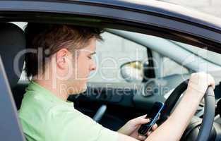 Concentrated man sending a text sitting in his car