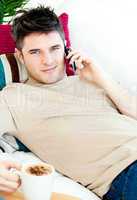 Handsome young man talking on phone at home
