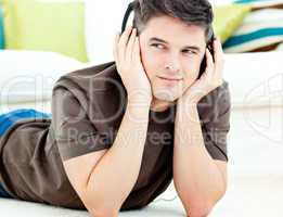 Attractive man listen to music lying on the floor