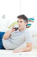 Positive young man drinking wine in the living-room