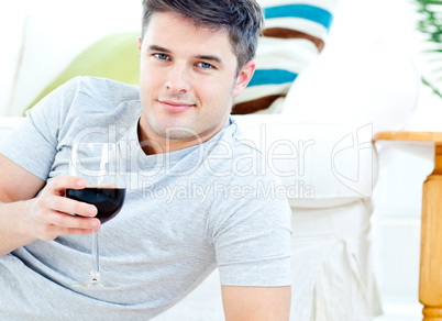Charming caucasian man holding a wineglass in the living-room