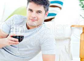 Charming caucasian man holding a wineglass in the living-room