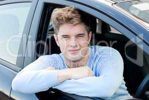 Positive young man sitting in his car