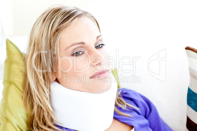 Beautiful woman wearing neckbrace lying on a sofa