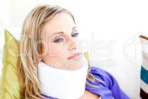 Beautiful woman wearing neckbrace lying on a sofa