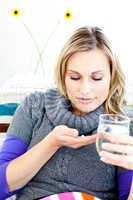 Sick woman taking pills holding a glass of water