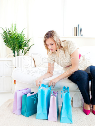Glowing young woman sitting on the sofa looking at her shopping