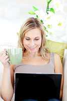 Caucasian woman sitting in front of her laptop and holding a cup