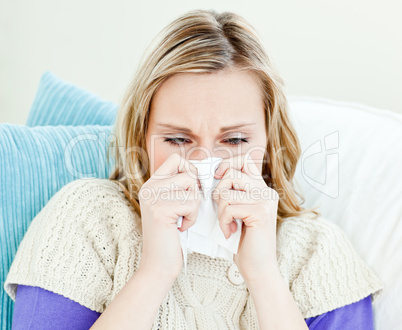 Portrait of a sick pretty woman blowing lying on a sofa