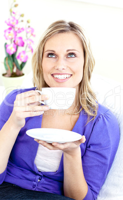 Bright woman enjoying her coffee sitting on the sofa