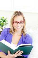 Portrait of a charming woman with glasses reading a book