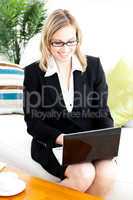 Ambitious businesswoman using her laptop sitting on the sofa