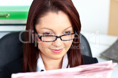 Delighted young businesswoman reading a newspaper