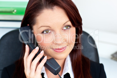 Assertive young businesswoman talking on phone smiling at the ca