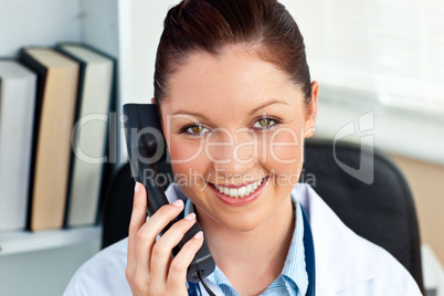 Smiling female doctor phoning in her office