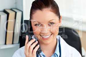 Smiling female doctor phoning in her office