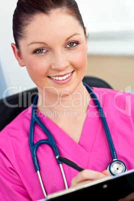 Serious female surgeon with a stethoscope writing in a clipboard