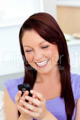 Bright woman texting with her cellphone on a sofa