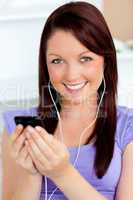 Happy woman using her cellphone to listen to music with earphone