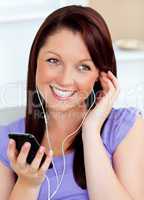 Happy woman using her cellphone to listen to music with earphone