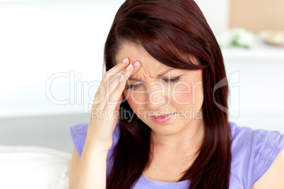 Caucasian woman with a headache sitting on a sofa at home