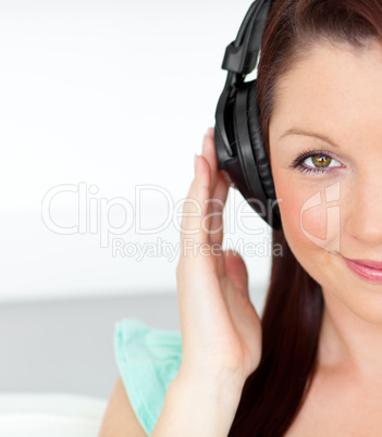 Pleased woman listening to music with headphones at home