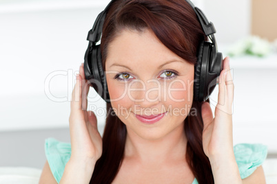 Bright woman listening to music with headphones at home