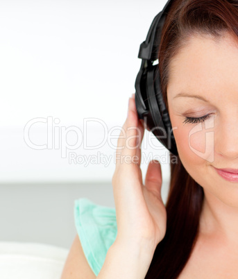 Delighted woman listening to music with headphones at home