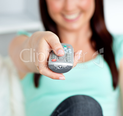 Close-up of a smiling woman hoding a remote in the living-room
