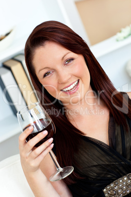 Smiling woman holding a wine of glass at home