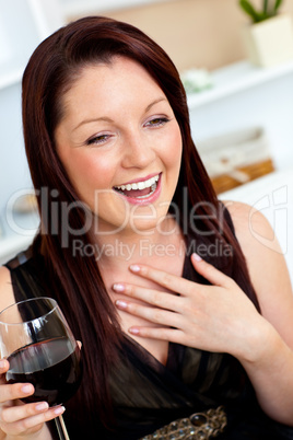 Delighted woman holding a wine of glass at home