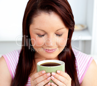 Delighted woman holding a cup of coffee at home