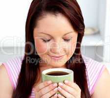 Delighted woman holding a cup of coffee at home
