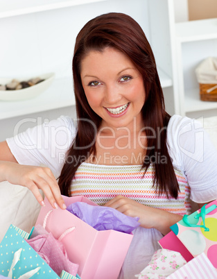 Happy caucasian woman opening her shopping bags on the sofa