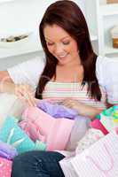 Smiling caucasian woman opening her shopping bags on the sofa