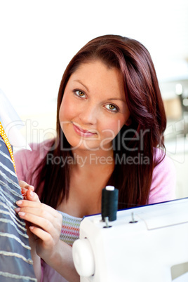 Attractive young caucasian woman sewing in the kitchen