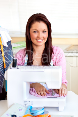 Young caucasian woman using a sewing-machine in the kitchen