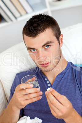 Deseased young man taking pills at home