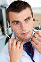 Confident male doctor holding a stethoscope in his office