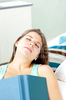 Sleeping woman lying on a sofa with a book