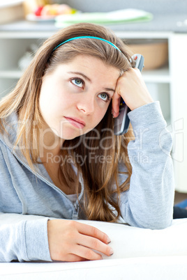 Bored young woman holdinga  remote sitting in the kitchen