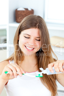 Merry woman using toothpaste in the bathroom
