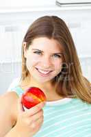 Pretty caucasian woman holding an apple at home