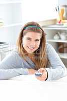 Charming young woman holding a  remote sitting in the kitchen