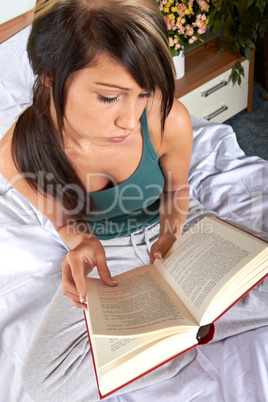 Frau mit Buch im Bett