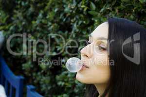 Girl in front of a green leaf blowing bubble