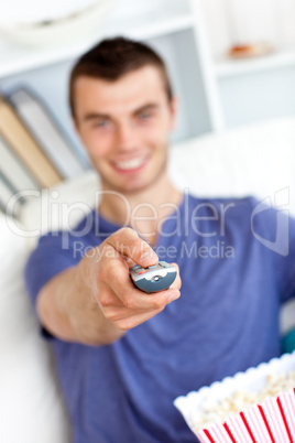 Positive caucasian man holding a remote looking at the camera in